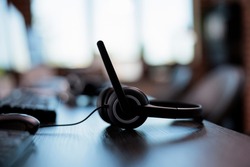 Call center equipment to chat with clients on telephone helpline at helpdesk. Customer service support headphones with microphone for telework and telemarketing assistance. Close up.