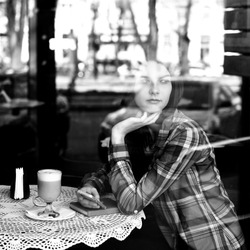 Young woman drinking coffee and use her smartphone sitting indoor in urban cafe. Cafe city lifestyle. Casual portrait of beautiful girl. Black and white