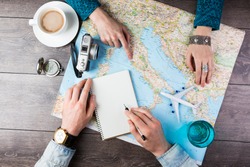 Two young people together planning trip to Europe. Top view. empty white space in notebook where you can place your text or advertisement.  Romantic travel