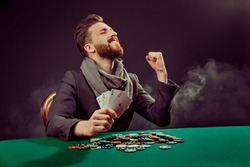 Successful poker player enjoying his win at poker table with chips and cards