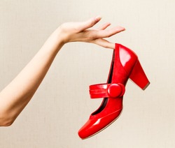 Woman hand holding dress red high heels shoe.