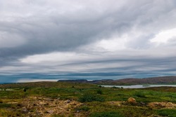 Polar landscape with granite stones and plants. North lake in the stone shore