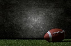 American football on green grass, on dark background. Team sport concept
