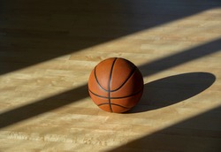 Basketball on hardwood court floor with natural lighting. Workout online concept