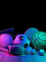 Sports equipment, rackets and balls on hardwood court floor with neon light background. Vertical education and sport poster, greeting cards, headers, website