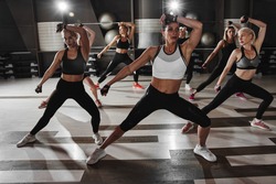 Women in black and white sportswear on a real group body Combat workout in the gym train to fight, kickboxing with a trainer