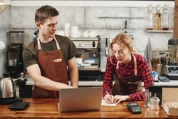 Two Barista boy and girl looking at laptop in a coffee shop. Training Intern