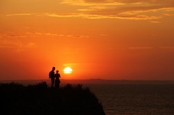 Beautiful scenic landscape - colorful sky with going down sun and young pair at the beach in Sunset in Taman, Krasnodar Krai, Azov sea, Russia august - 2012 - stock photo