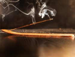 Stick Holder and Incense Stick with Smoke on Black Background. Pure relaxation theme.