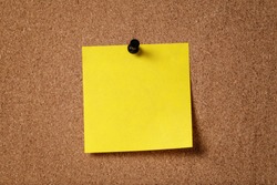 yellow reminder sticky note on cork board, empty space for text