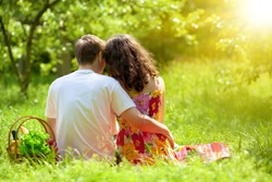 Young couple sitting back to camera on picnic blanket