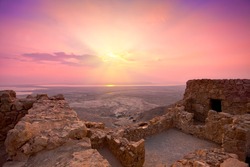 Beautiful purple sunrise over Masada fortress. Ruins of King Herod's palace in Judaean Desert.