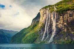 Mountain landscape with cloudy sky. Beautiful nature Norway. Geiranger fjord. Seven Sisters Waterfall