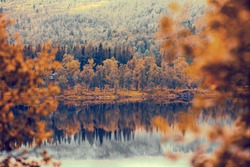 Rocky bank of mountain lake in misty autumn morning. Beautiful autumn nature of Norway. Reflection on the lake