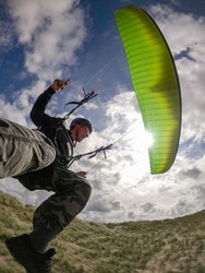 Paraglider pilot close up soaring in Netherlands dunes at sunny day 