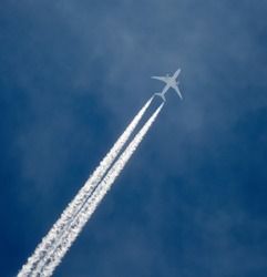 Jet airplane in the sky, leaving vapor trails behind in flight