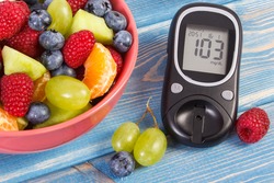 Fresh fruit salad and glucometer with result of measurement sugar level, concept of diabetes, diet, slimming, healthy lifestyles and nutrition