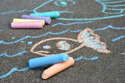 Colorful sidewalk chalk with sketched fish in background.  Close-up with shallow dof.  Focus on foreground.