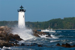 Portsmouth harbor lighthouse, also known as Fort Constitution light, guides a fishing boat through rough seas into the harbor in seacoast New Hampshire. A favorite tourist attraction in New England.