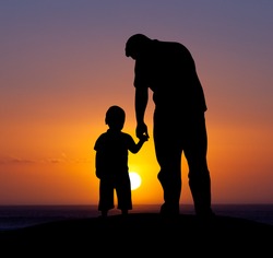 Silhouette of a man and his son with sunset background.