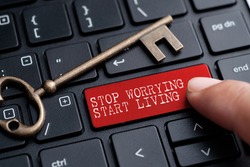 Closed up finger on keyboard with word STOP WORRYING, START LIVING.