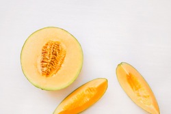 Ripe melon half and  slices on white background, top view, blank space 