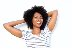 Close up portrait of happy young black woman with hands behind hair and smiling on white background