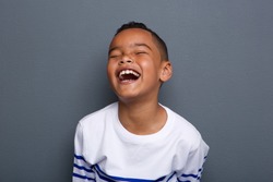 Close up portrait of an excited little boy laughing on gray background