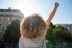 Portrait from behind young african american woman with arm raised fist