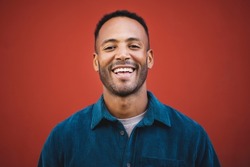 Cheerful african american man laughing over maroon background