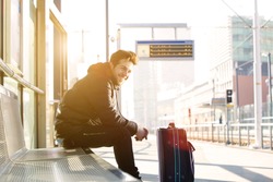 Portrait of a happy young man waiting for train at station with bag