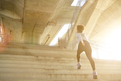 Young exercise woman running alone up stairs 