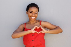Portrait of smiling young african american woman with heart shape hand sign 