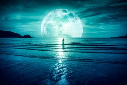 Super moon. Colorful sky with bright full moon over seascape and silhouette of woman standing in the sea . Serenity nature background, outdoor at gloaming. The moon taken with my own camera.