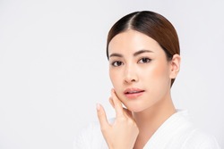 Youthful radiant pretty Asian woman with hand touching face on white background for beauty and skin care concepts