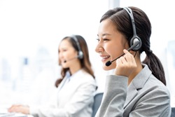 Smiling telemarketing Asian woman working in call center office
