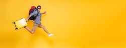 Young excited Caucasian male tourist with baggage jumping in mid-air run to vacation isolated on colorful studio yellow banner background