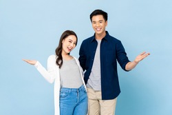 Portrait of happy cheerful awesome Asian couple with big smiles opening hands on isolated light blue background