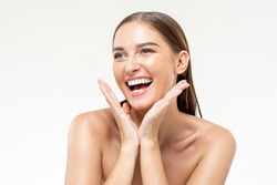 Beauty shot of young smiling positive Caucasian woman with hands touching face in isolated white studio background