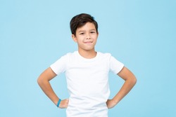 Cute mixed race boy smiling with arms akimbo in studio isolated light blue color background