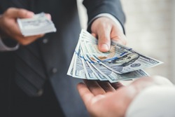 Businessman giving or paying money to a man, US dollar (USD) bills - lending, loan and financial concepts
