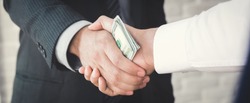 Businessmen making handshake with money in hands - bribery, corruption and venality concepts