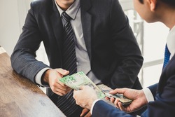 Businessman giving money, Australian dollar bills, to his partner - loan, bribery and corruption concepts