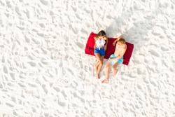 Top view of couple lying on white sand beach taking a sunbath in summer 