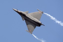 Dassault Rafale fighter jet flying with smoke trails.