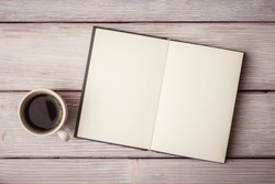 Open notebook with cup of coffee on wooden desk
