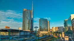 Milan skyline with modern skyscrapers in Porta Nuova business district timelapse in Milan, Italy, at sunset with orange light. Traffic on the road. Light in windows. Top view from bridge