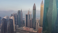 Financial center of Dubai city with luxury skyscrapers and big parking morning timelapse, Dubai, United Arab Emirates. Aerial view with office towers and reflections from glass surface during sunrise