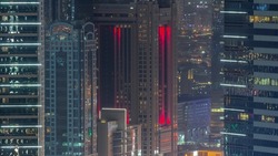 Glowing windows and towers with glass surface aerial view. Financial center of Dubai city with illuminated luxury skyscrapers night timelapse, Dubai, United Arab Emirates.