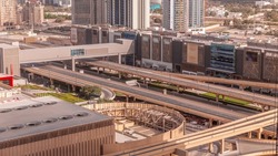 Highway road traffic on overpass under footbridge near shopping mall in Dubai downtown timelapse, UAE. Aerial view from rooftop of skyscraper with modern buildings